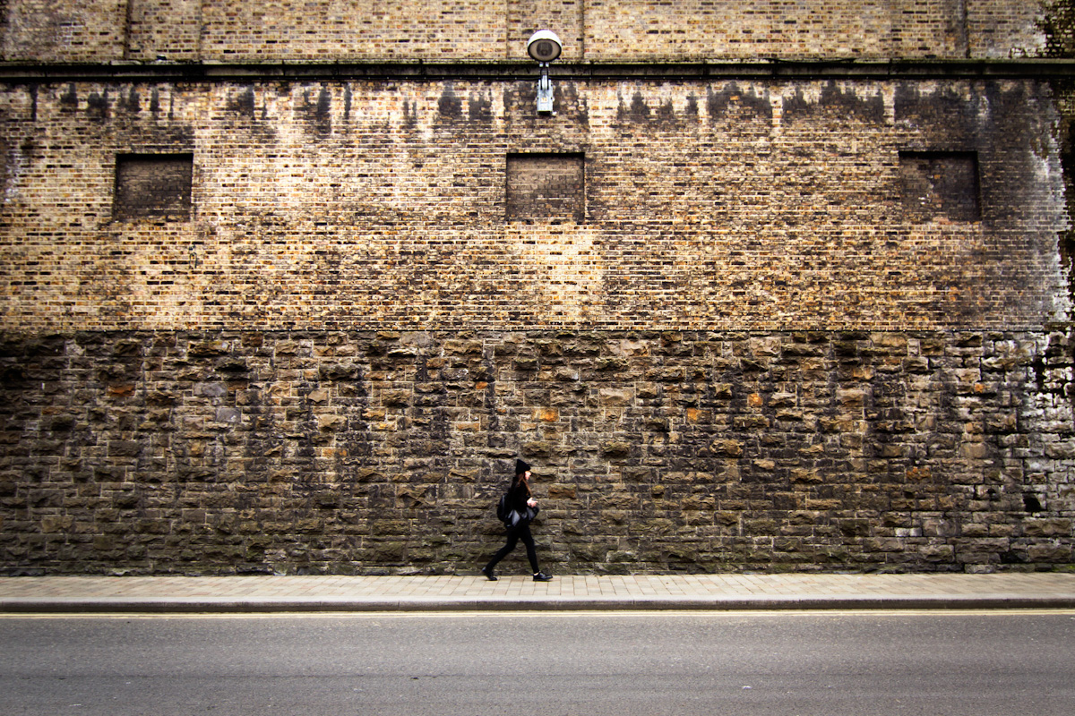 A girl walks lonely in front of the walls of the Guiness Factory, Dublin.